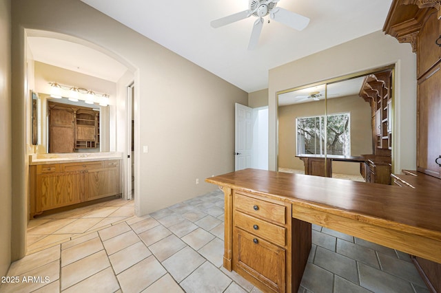 home office featuring light tile patterned flooring, arched walkways, and ceiling fan