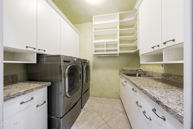 laundry area featuring light tile patterned floors, washer and dryer, cabinet space, and a sink