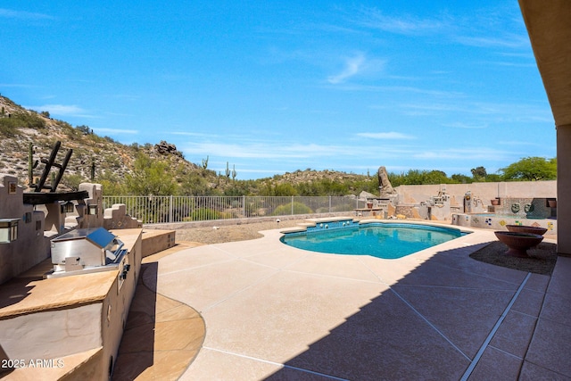 view of swimming pool with a fenced in pool, a fenced backyard, a patio area, and an outdoor kitchen