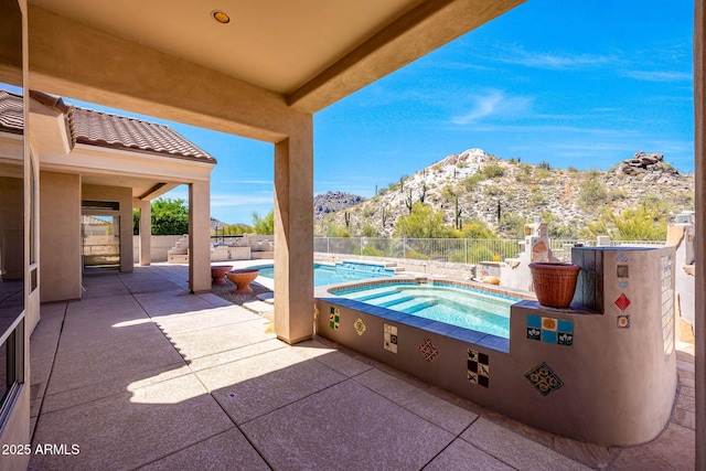 view of patio featuring a mountain view, a fenced in pool, an in ground hot tub, and a fenced backyard