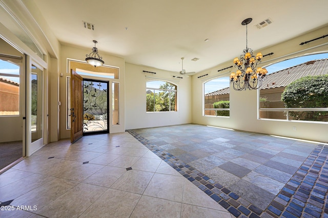 tiled entryway featuring an inviting chandelier, visible vents, and baseboards