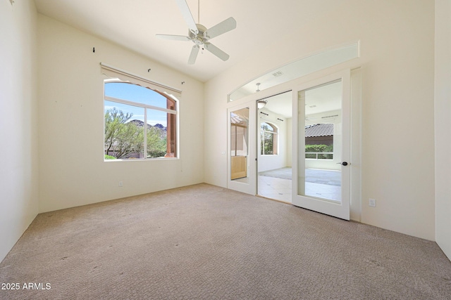 empty room featuring french doors, a ceiling fan, and light carpet