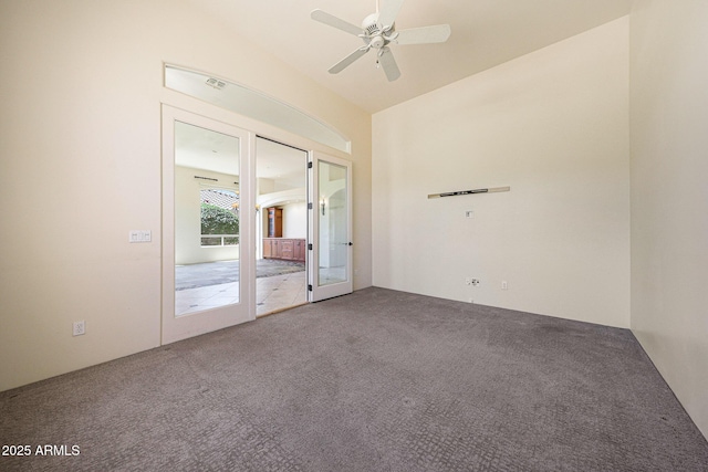 carpeted spare room with a ceiling fan, visible vents, vaulted ceiling, and french doors