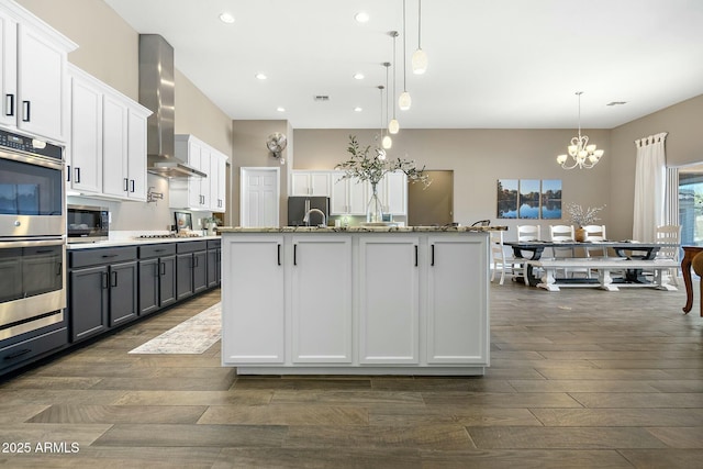 kitchen with stainless steel appliances, gray cabinets, white cabinets, and wall chimney exhaust hood