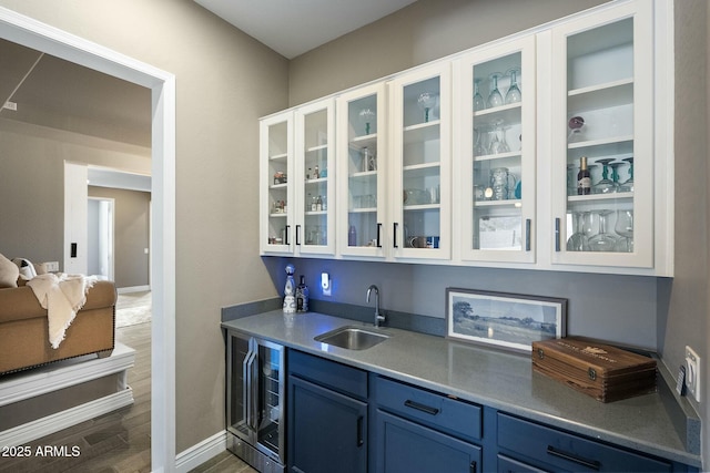 bar with wine cooler, a sink, baseboards, dark wood-style floors, and indoor wet bar