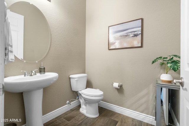 bathroom featuring a sink, wood finished floors, toilet, and baseboards