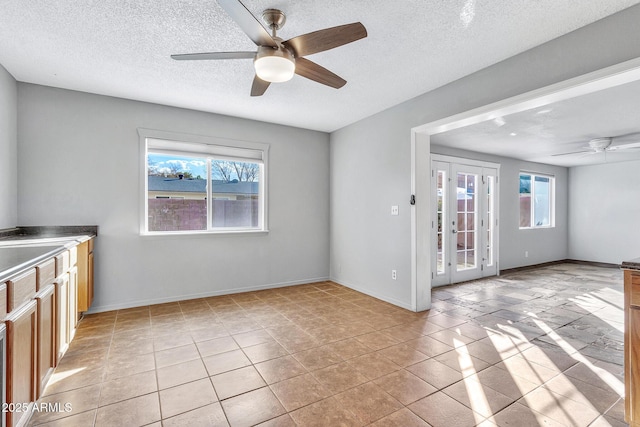 interior space with plenty of natural light, a textured ceiling, ceiling fan, and french doors