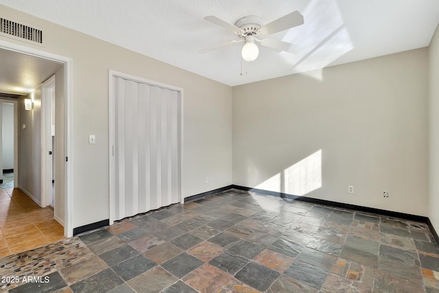 empty room with ceiling fan and a textured ceiling