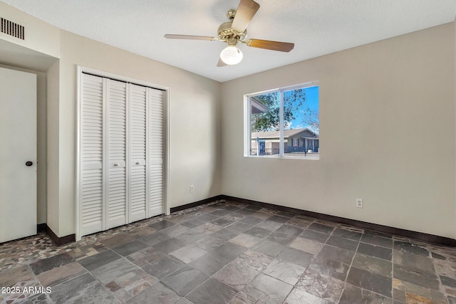 unfurnished bedroom with a textured ceiling, ceiling fan, and a closet