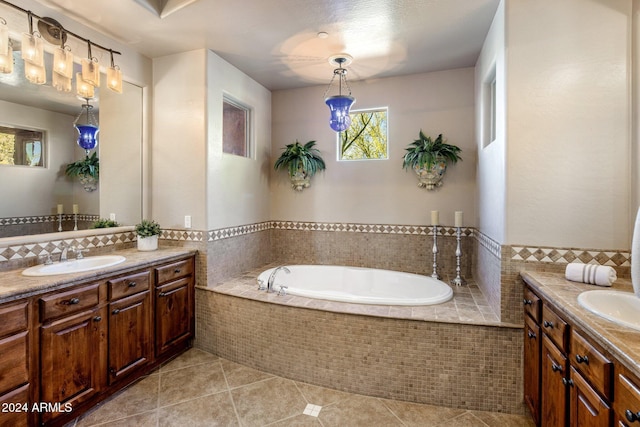 bathroom with tile patterned floors, vanity, a relaxing tiled tub, and tile walls