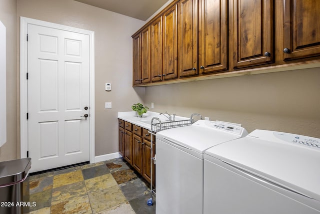 washroom with cabinets, washer and dryer, and sink