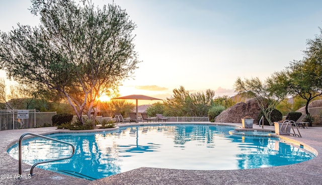 pool at dusk with a patio area