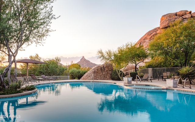 pool at dusk featuring a mountain view and a patio