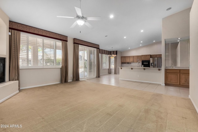 unfurnished living room featuring ceiling fan, light colored carpet, lofted ceiling, and sink