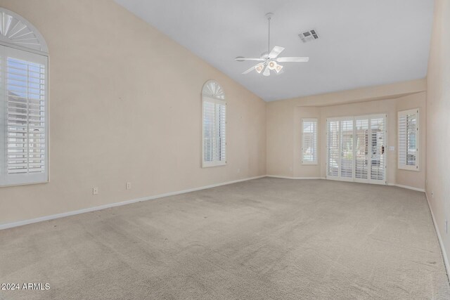 carpeted empty room featuring ceiling fan, a wealth of natural light, and vaulted ceiling