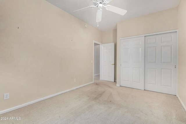 unfurnished bedroom featuring light carpet, a closet, and ceiling fan