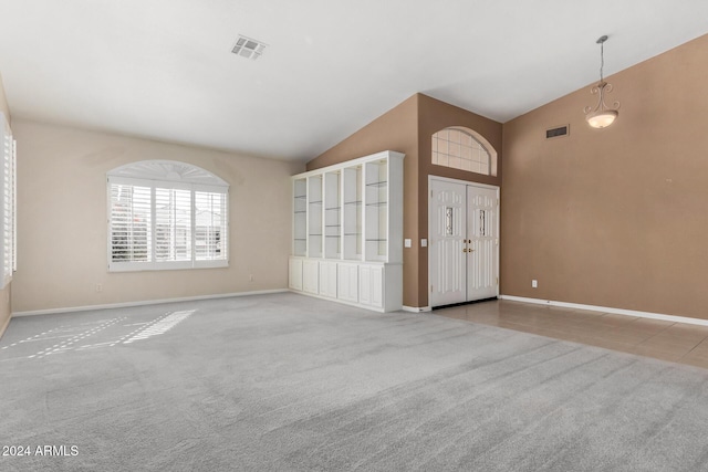 empty room with high vaulted ceiling and light colored carpet