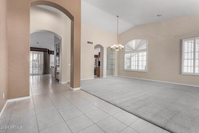 unfurnished room with a notable chandelier, light tile patterned floors, and vaulted ceiling