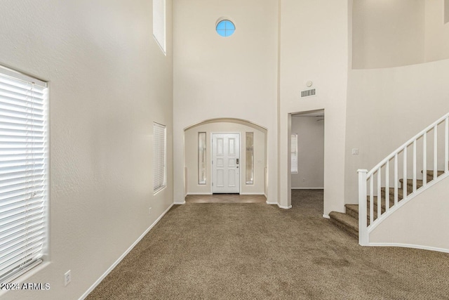 entryway featuring carpet and a towering ceiling