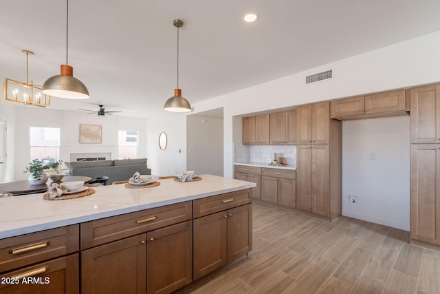 3837 E Windsong Dr, Phoenix, AZ 85048 - kitchen with a ceiling fan, pendant lighting, a fireplace, backsplash, and open floor plan