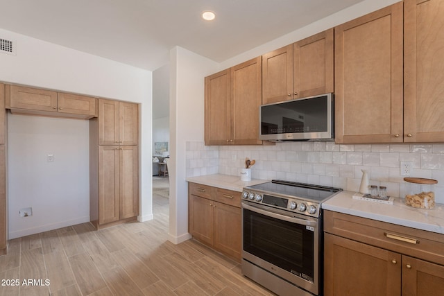3837 E Windsong Dr, Phoenix, AZ 85048 - kitchen with appliances with stainless steel finishes, light countertops, backsplash, light wood finished floors, and baseboards