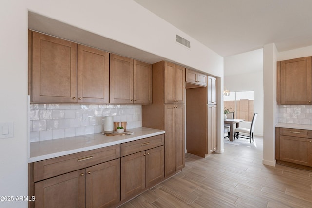 3837 E Windsong Dr, Phoenix, AZ 85048 - kitchen with decorative backsplash, light countertops, light wood finished floors, and brown cabinets