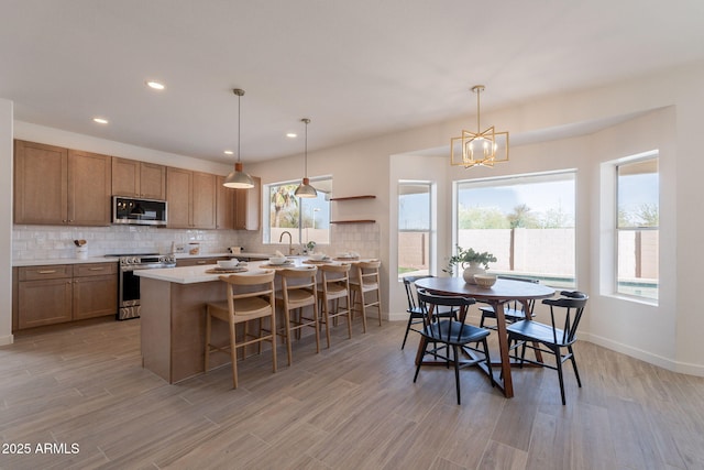 3837 E Windsong Dr, Phoenix, AZ 85048 - kitchen featuring stainless steel appliances, light countertops, tasteful backsplash, a sink, and light wood-type flooring