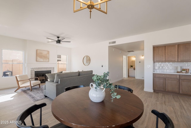 3837 E Windsong Dr, Phoenix, AZ 85048 - dining room featuring light wood-style floors, ceiling fan, baseboards, and a tile fireplace