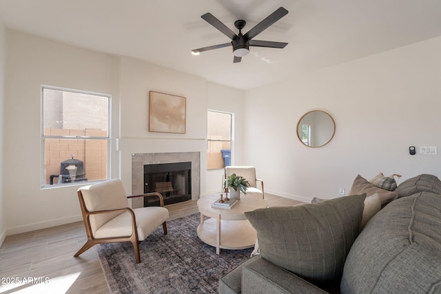 3837 E Windsong Dr, Phoenix, AZ 85048 - living area featuring a tiled fireplace, ceiling fan, light wood-style floors, and baseboards