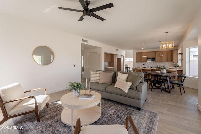 3837 E Windsong Dr, Phoenix, AZ 85048 - living area featuring a ceiling fan, baseboards, a chandelier, and light wood finished floors