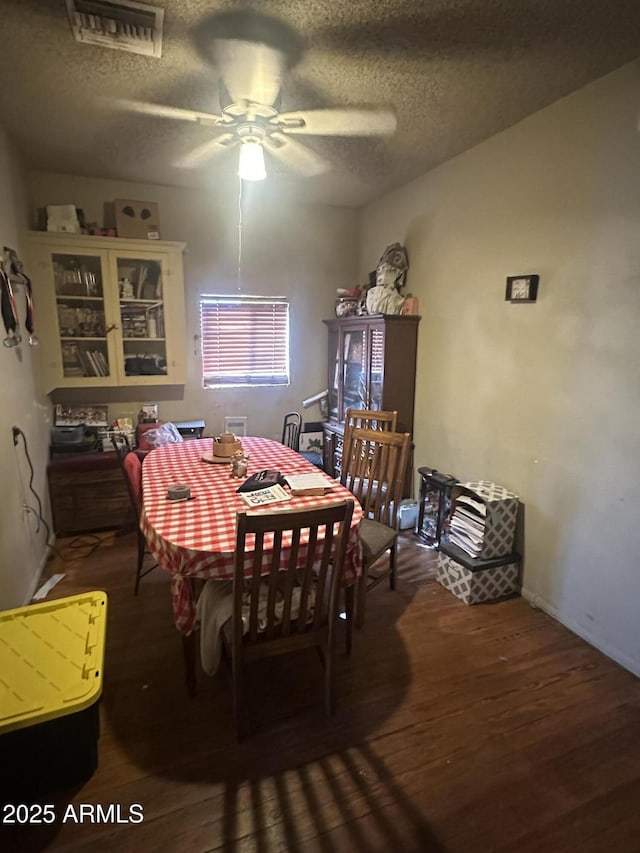 dining room featuring ceiling fan, a textured ceiling, visible vents, and wood finished floors