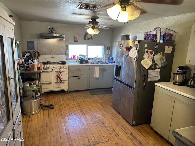 kitchen with range with two ovens, light wood-type flooring, visible vents, and stainless steel refrigerator with ice dispenser