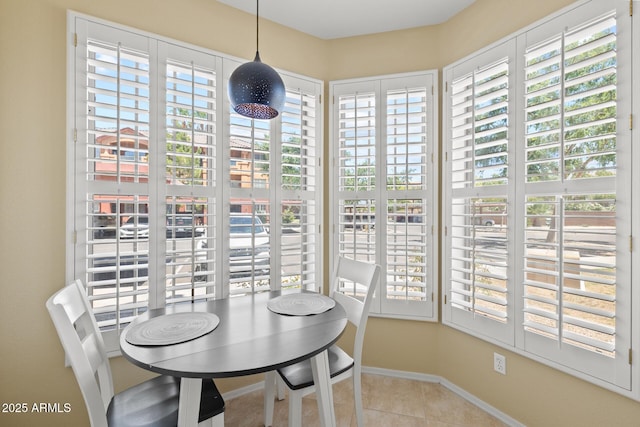 tiled dining space with baseboards and a wealth of natural light