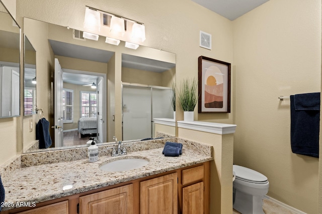 ensuite bathroom featuring ceiling fan, vanity, toilet, a shower stall, and visible vents