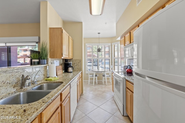 kitchen featuring decorative backsplash, white appliances, light stone counters, a sink, and light tile patterned floors