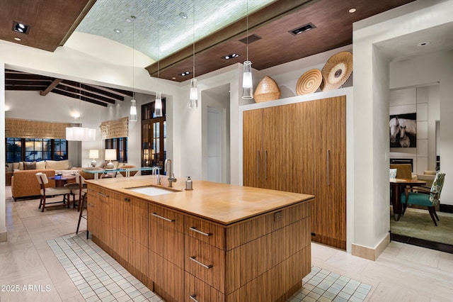 kitchen with modern cabinets, a spacious island, a sink, vaulted ceiling, and decorative light fixtures