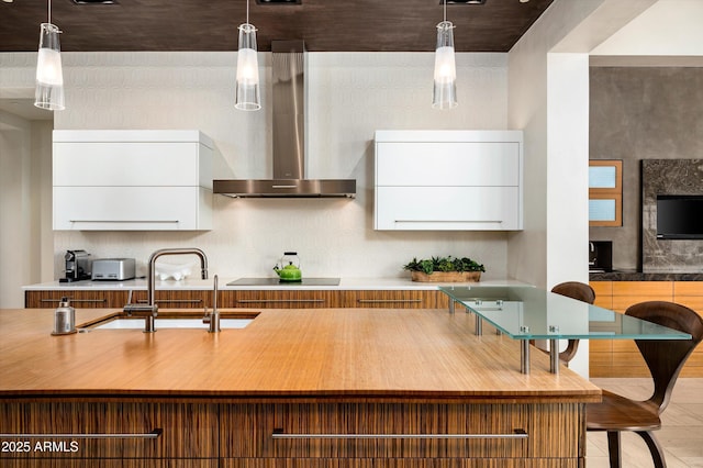 kitchen featuring wall chimney range hood, white cabinets, black electric stovetop, a sink, and modern cabinets