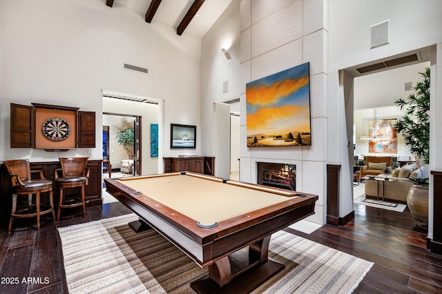 game room with visible vents, a large fireplace, high vaulted ceiling, beamed ceiling, and dark wood-style floors