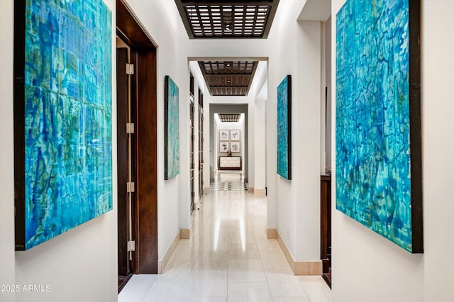 corridor with baseboards and tile patterned floors