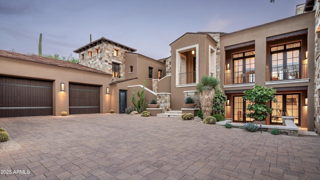 view of front of property featuring decorative driveway, a garage, and stucco siding
