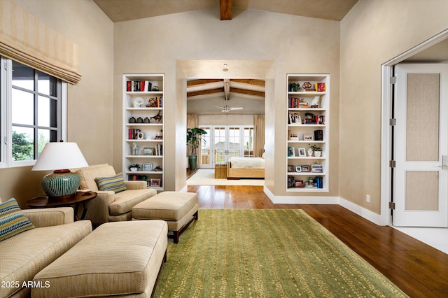 living area featuring vaulted ceiling with beams, wood-type flooring, baseboards, and built in shelves