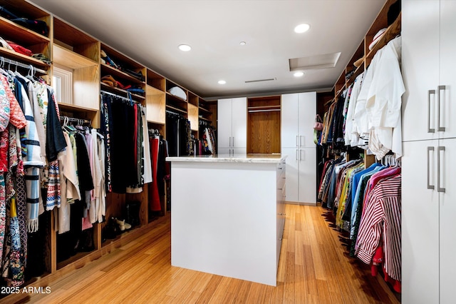 walk in closet featuring light wood-style floors and attic access