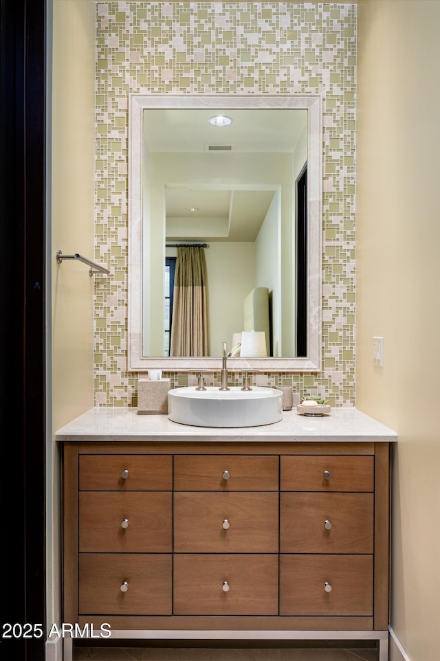 bathroom featuring vanity, decorative backsplash, and visible vents