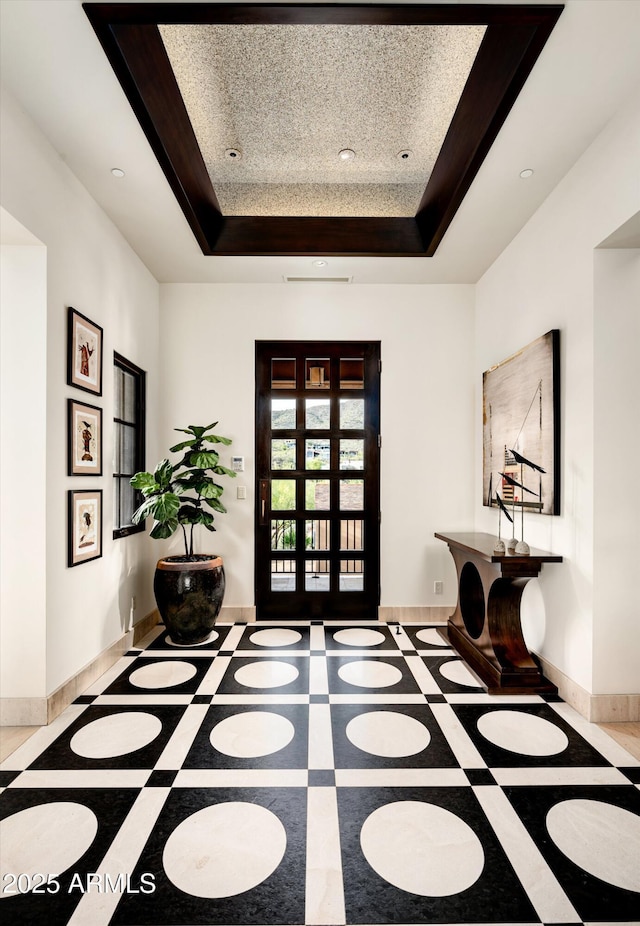 entryway with baseboards, recessed lighting, and a tray ceiling