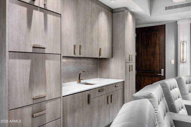 kitchen with a sink, light countertops, backsplash, visible vents, and modern cabinets