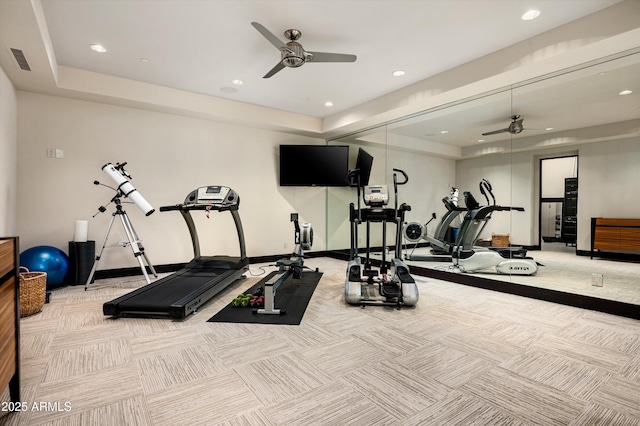 gym with visible vents, a raised ceiling, and ceiling fan