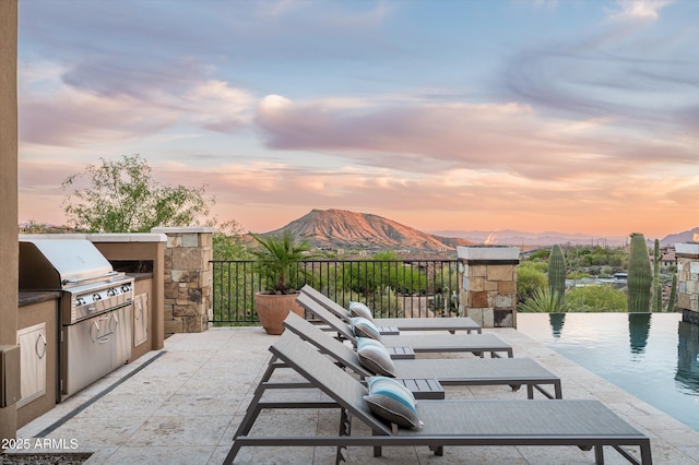 view of patio / terrace with exterior kitchen, a mountain view, and a grill