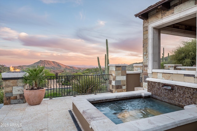 view of patio with an in ground hot tub and a mountain view