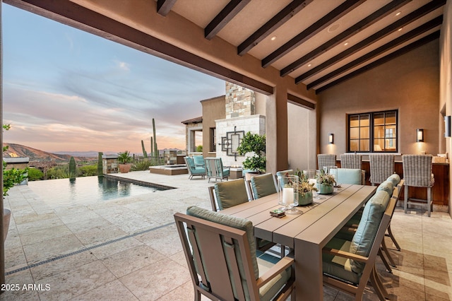 patio terrace at dusk featuring an outdoor pool and outdoor dining space