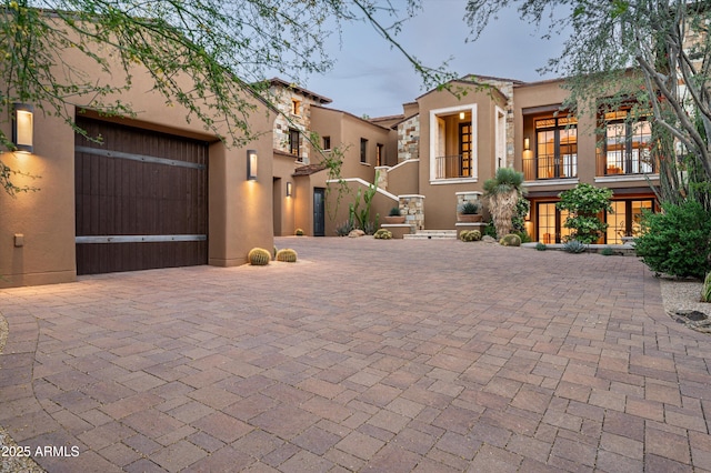 view of front of property with decorative driveway, a garage, and stucco siding